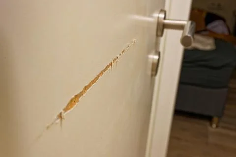 Damaged interior door with visible scratch and peeled paint showing home re.. Stock Photos