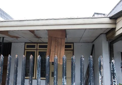 Damaged old house with collapsed ceiling behind a fence Stock Photos