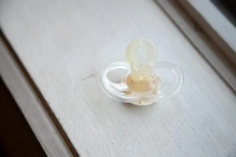 A damaged pacifier lies on a surface, symbolizing the end of a phase. Stock Photos