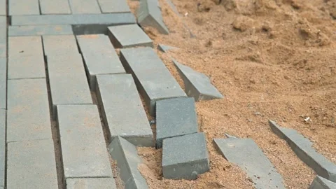 Damaged pathway where stones are unevenly placed on a sandy surface. The area Stockbeeldmateriaal 344675407