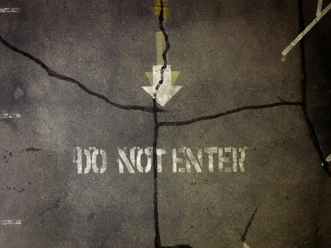 Damaged pavement features spray-painted warning text Fotos Stock