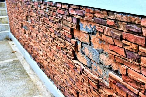 Damaged red brick wall with missing bricks Stock Photos