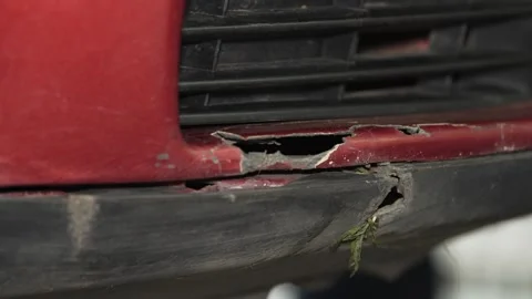 Damaged red car front bumper with cracks and broken plastic. Stock Footage 341487162