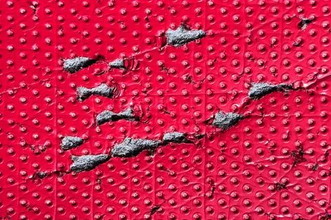 Damaged red textured surface with dotted patterns and gray foam material Stock Photos
