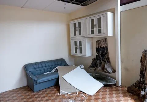 A damaged room with a broken section of ceiling and debris scattered on the.. Stock-Fotos