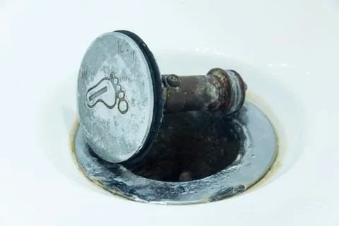 Damaged sewer hole with corrosion elements on which lies a broken metal butto 스톡 사진
