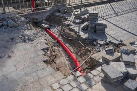 Damaged sidewalk section with paving blocks removed, showing underground utility Foto stock