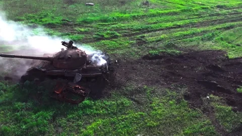 Damaged tank exploding and burning on a green field 库存影片 313255417
