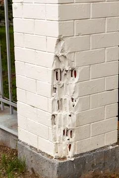 Damaged white brick wall corner with significant cracks and broken structure Stock-Fotos