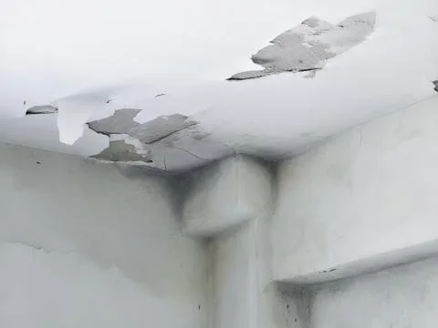 Damaged white ceiling showing peeling paint and deep cracks Stock Photos