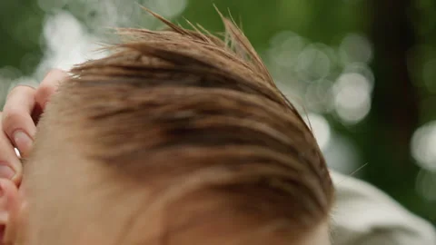 Damp hair styling under cloudy sky, Closeup of man adjusting wet hair outside in Stock Footage 327272454