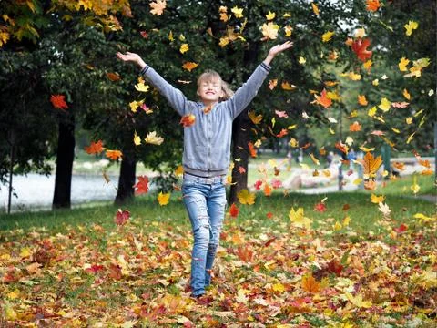 Dance in the autumn leaf fall. Young beautiful girl playing with autumn leave Stock Photos