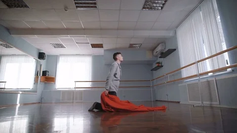 Dance with a big red cloth. The man falls on a red cloth. Beautiful movement Stock Footage 70386787