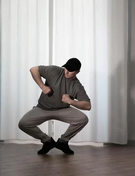 Dance in motion, pose of a man in hip-hop style clothes. Sports dancing guy.. Stock Photos