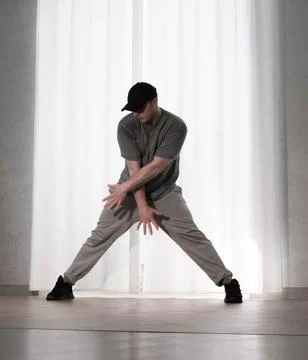 Dance in motion, pose of a man in hip-hop style clothes. Sports dancing guy.. Stock Photos