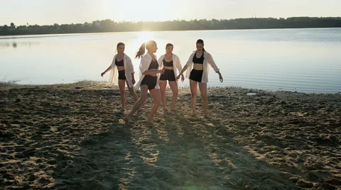 Dance performance of four girls on sand beach near lake at dawn Stock Footage 65293025