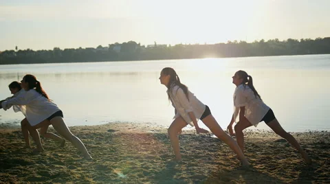Dance performance of four girls on sand beach near lake at dawn Stock Footage 65295871