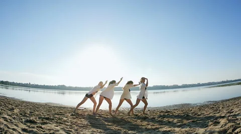 Dance performance of four girls on sand beach near lake at dawn Stock Footage 65299498
