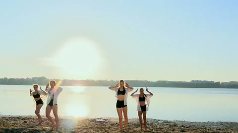 Dance performance of four girls on sand beach near lake at dawn Stock Footage 65320728