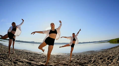 Dance performance of four girls on sand beach near lake at dawn Видео 65321538