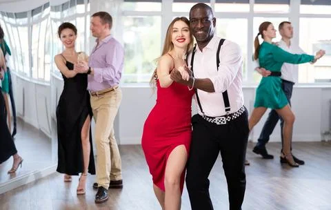 Dance studio - group of beautifully dressed people learn to dance tango Stock Photos