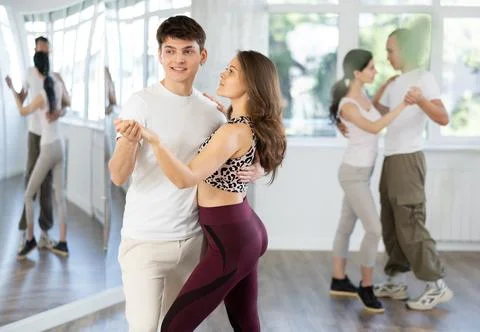 Dance studio - students in casual clothes learn to dance tango Stock Photos