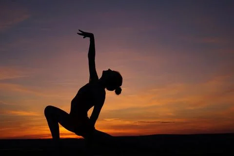 Dancer in the dance does the splits in the air against the sunset. Stock Photos