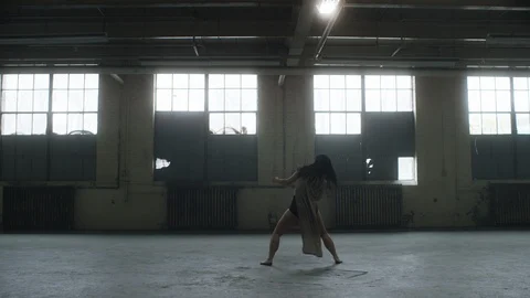 Dancer dances in industrial warehouse with passion, then falls to the ground 스톡 동영상 104464985