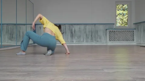 Dancer dances sitting on the floor legs wide apart and making sweeping movements Stock Footage 287099626