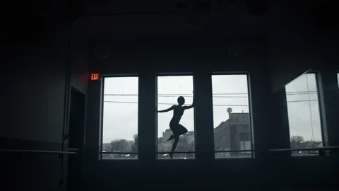 Dancer dancing on window sill in large dark moody dance studio Stock Footage 104275086