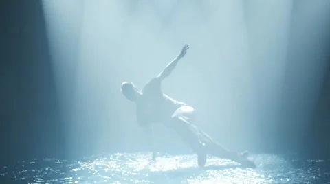 Dancer does a break-dance in the water in a circle of light Stock Footage 64045293