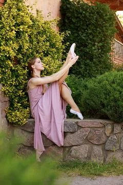 Dancer does the stretch while sitting in the botanical garden. 스톡 사진
