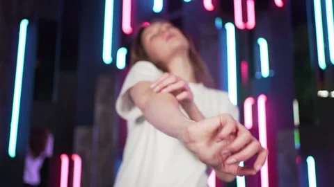 The dancer enjoys the party, hands in focus. Dance to music against neon Stock Footage 146573768