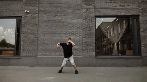 A dancer in gray shorts and a black T-shirt with glasses dances against the Stock Footage 250590965