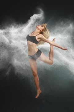 Dancer jumping into white powder cloud Stock Photos