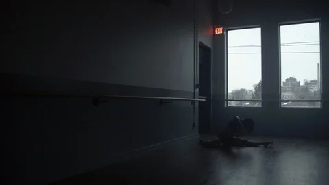 Dancer in large open modern dance studio on floor warms up and stretches Vídeo Stock 104273848