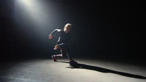 A dancer makes elegant circular movements in the dark Stock Footage 210545504