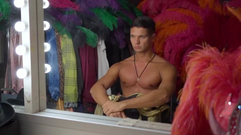 Dancer man with a bare torso straightens his shoulders in front of the mirror in Stock Footage 150126036
