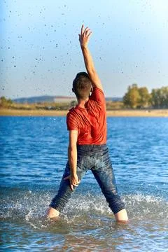 Dancer man with his back wet in a lake with a red shirt. Stock Photos