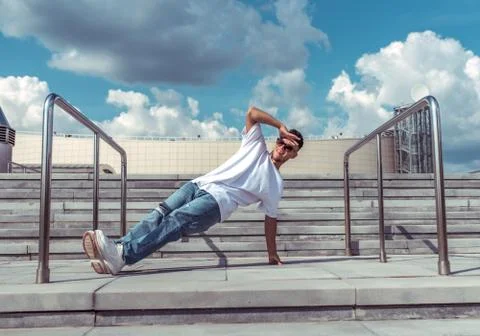 Dancer on one arm dances break dance, hip-hop. In summer, city background steps Stock Photos