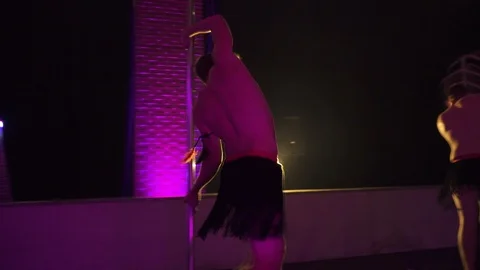Dancer performing pole dance in club, spins on a pole with purple background Stock Footage 121461159