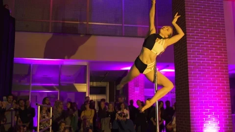 Dancer performing pole dance in club, spins on a pole with purple background Stock Footage 121461291