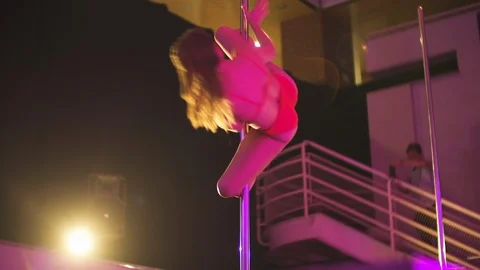 Dancer performing pole dance in club, spins on a pole with purple background Stock Footage 121461725