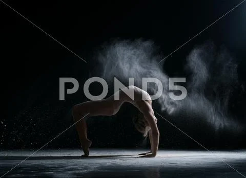 Dancer performs acrobatic trick in cloud of dust Stock Photos