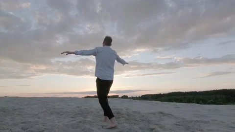 Dancer performs contemporary choreography on the sand at sunset. Slow motion Stock Footage 135610508