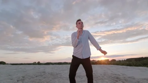 Dancer performs contemporary choreography on the sand at sunset. Slow motion Stock Footage 135610513