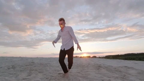 Dancer performs contemporary choreography on the sand at sunset. Slow motion Stock Footage 135610556