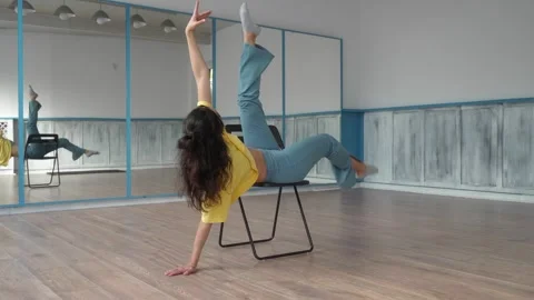 The dancer performs the dance lying on a chair, gracefully lifting her legs. Stock Footage 287099277