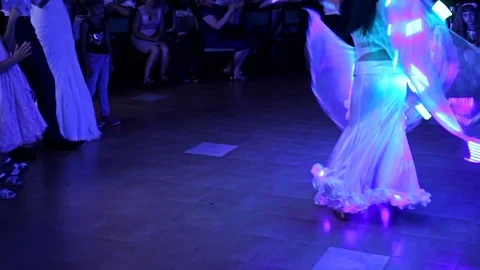 Dancer performs a dance in a restaurant in a glowing outfit Vídeo Stock 79673575