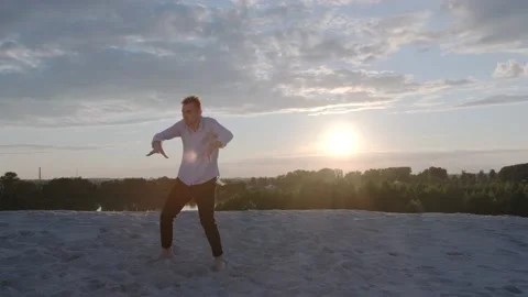 Dancer performs a freestyle dance composition on the sandy beach at sunset Stock Footage 135610862